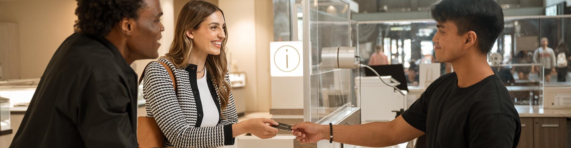 Smiling couple handed a gift card at a mall information desk by staff