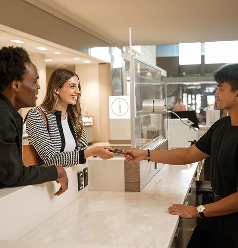 Smiling couple handed a gift card at a mall information desk by staff