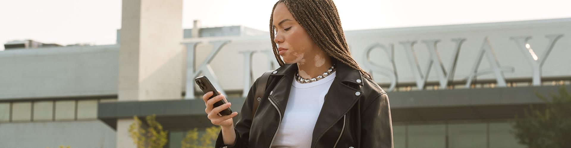 Woman in a leather jacket looking at her phone outside the Kingsway mall