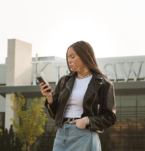 Woman in a leather jacket looking at her phone outside the Kingsway mall