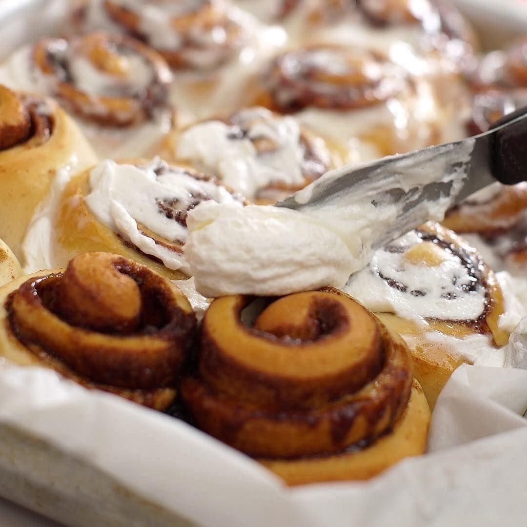 Cinnamon buns getting frosting