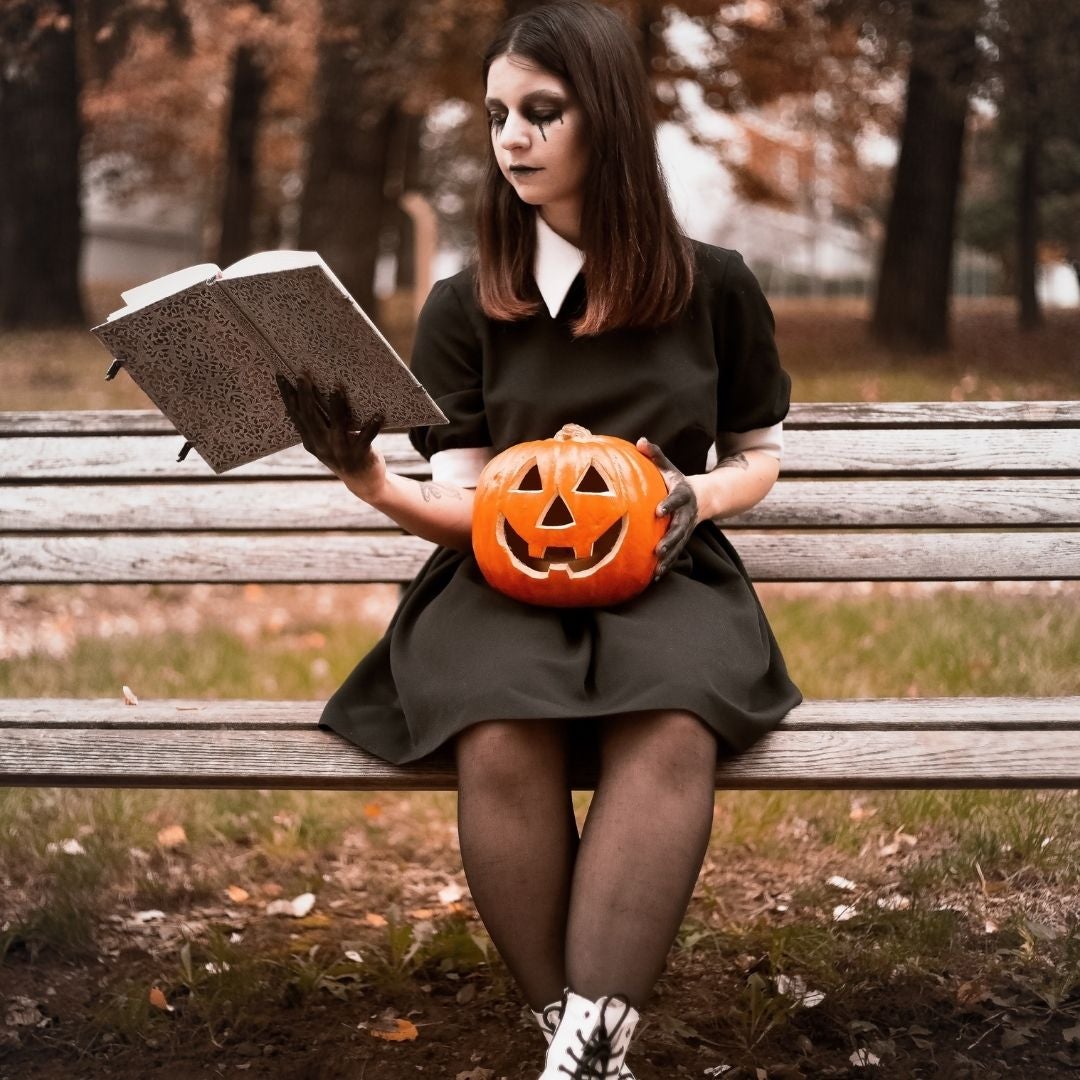 Girl in a black dress holding a pumpkin