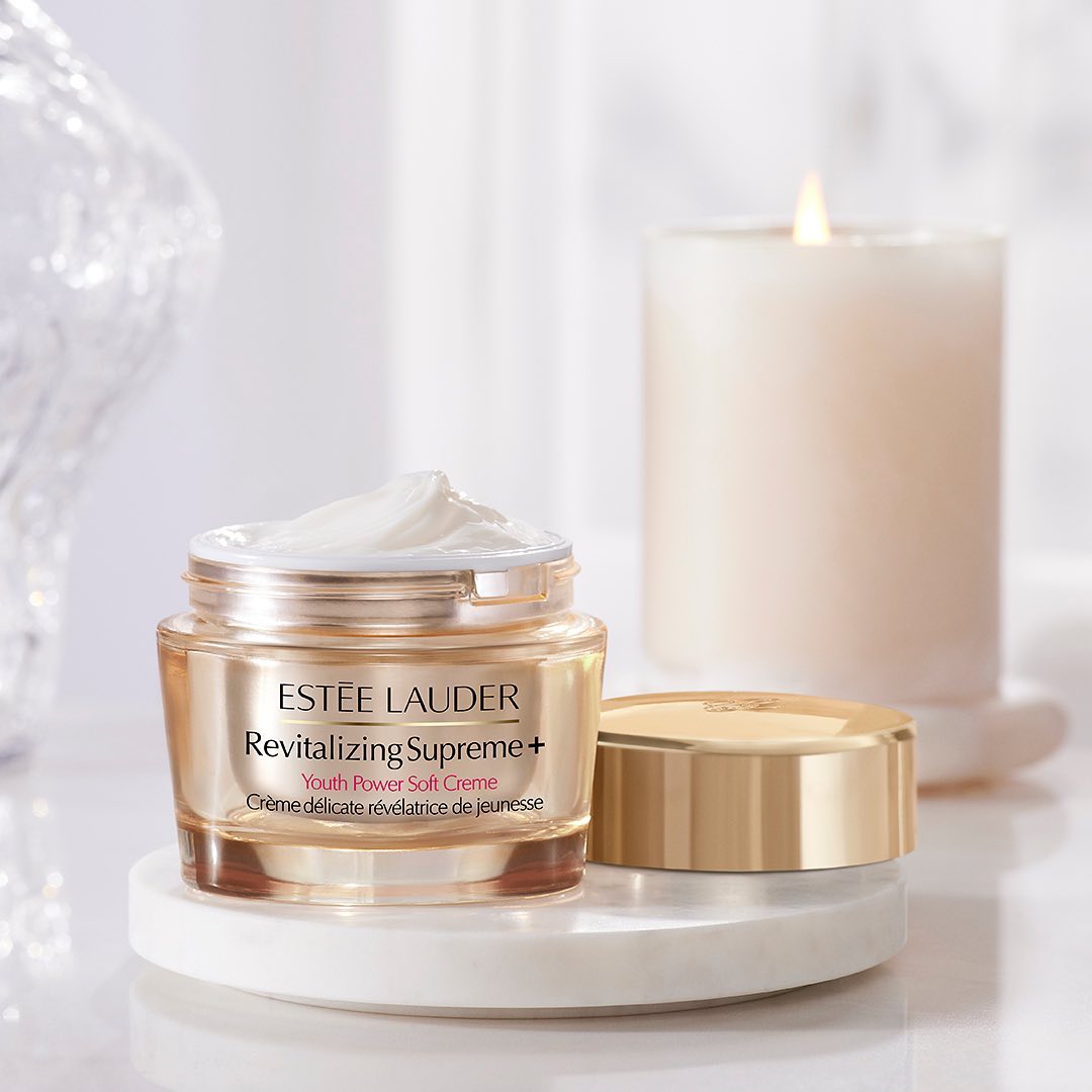 Estee Lauder face cream is showcased on a white background alongside a white candle.