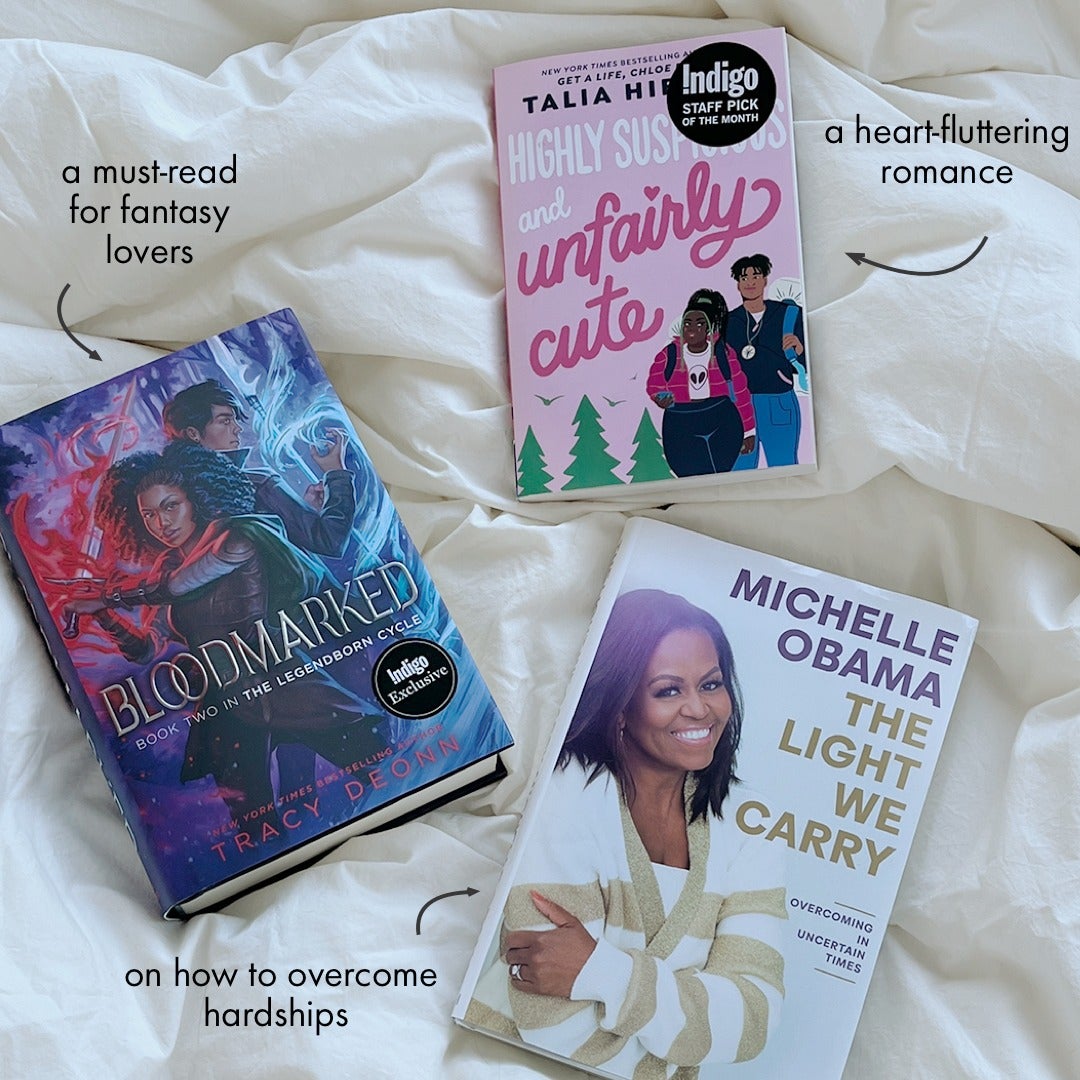 Three different books are laid out on a white duvet.