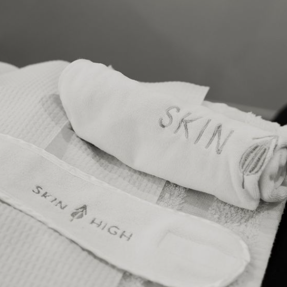 A white Skin High branded towel is rolled op.