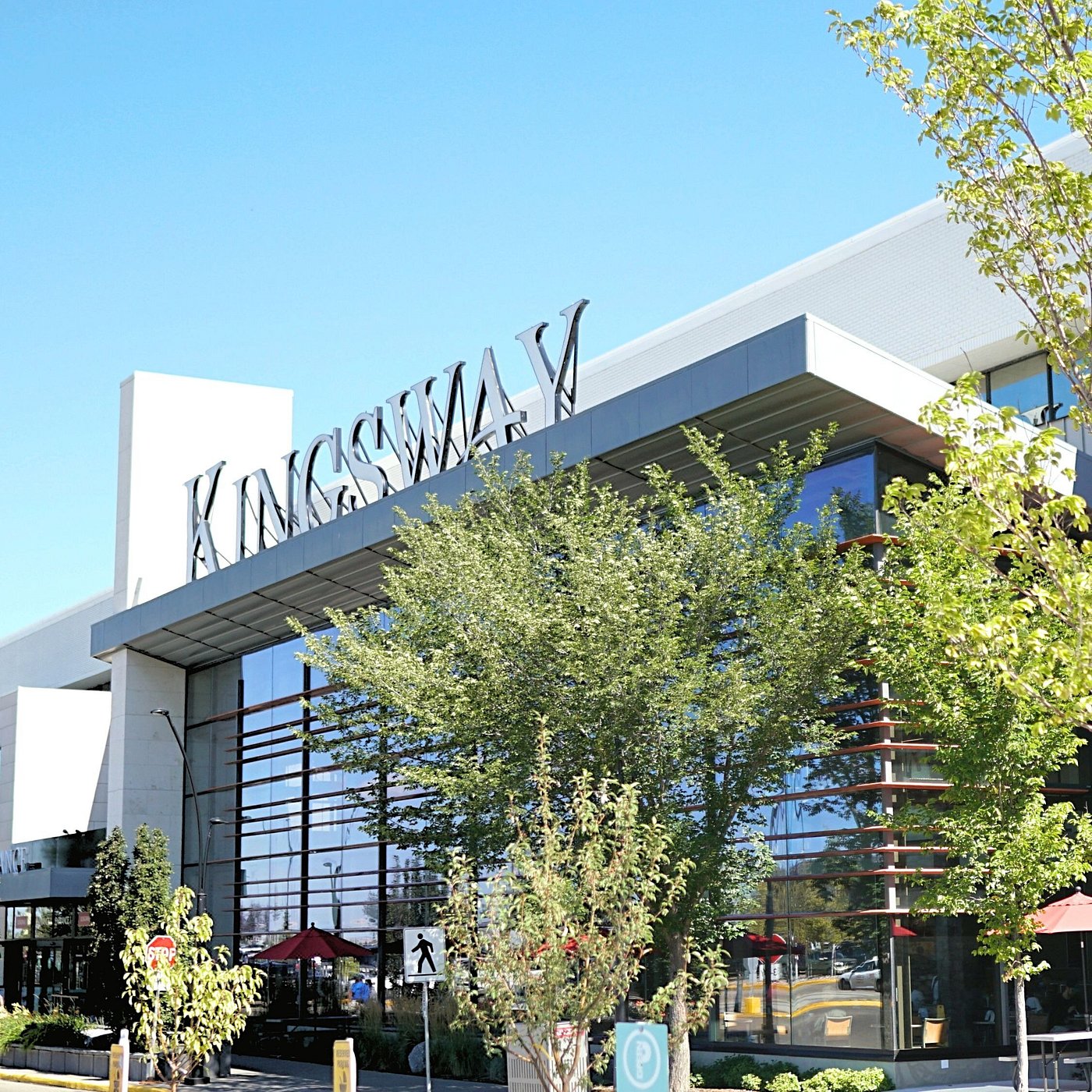 An image of the exterior of Kingsway Mall on a sunny day. The sky is clear and blue and trees surround the building.