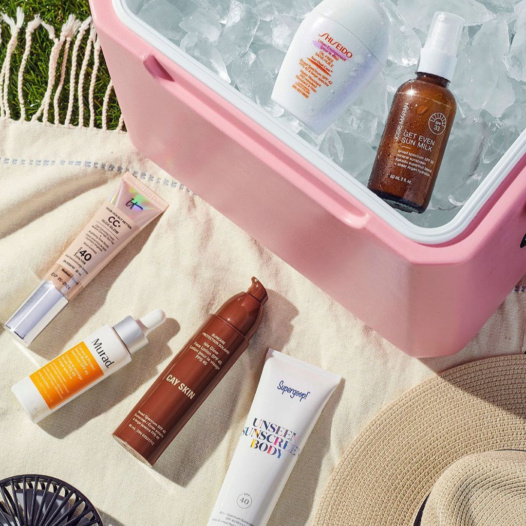 stylized image of summer beauty products. two products are in a pink cooler filled with ice, while four others are on a picnic blanket
