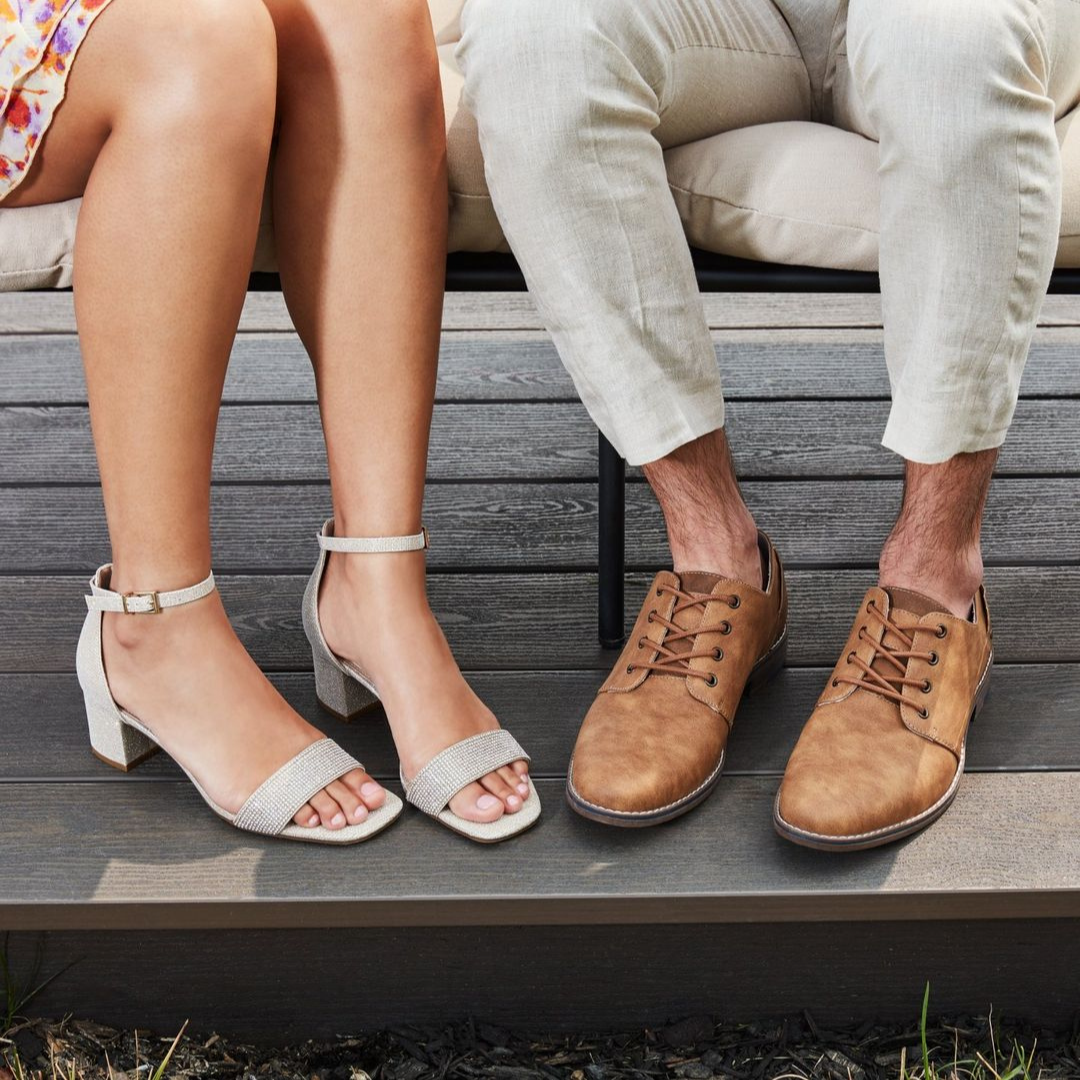 close-up image of a woman and a man's legs and feet. the woman is on the left and wears sparkly block heel sandals and the man on the right wears brown dress shoes