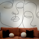 brown couch with decor pillows in front of one line drawing of two faces on wall at a spa