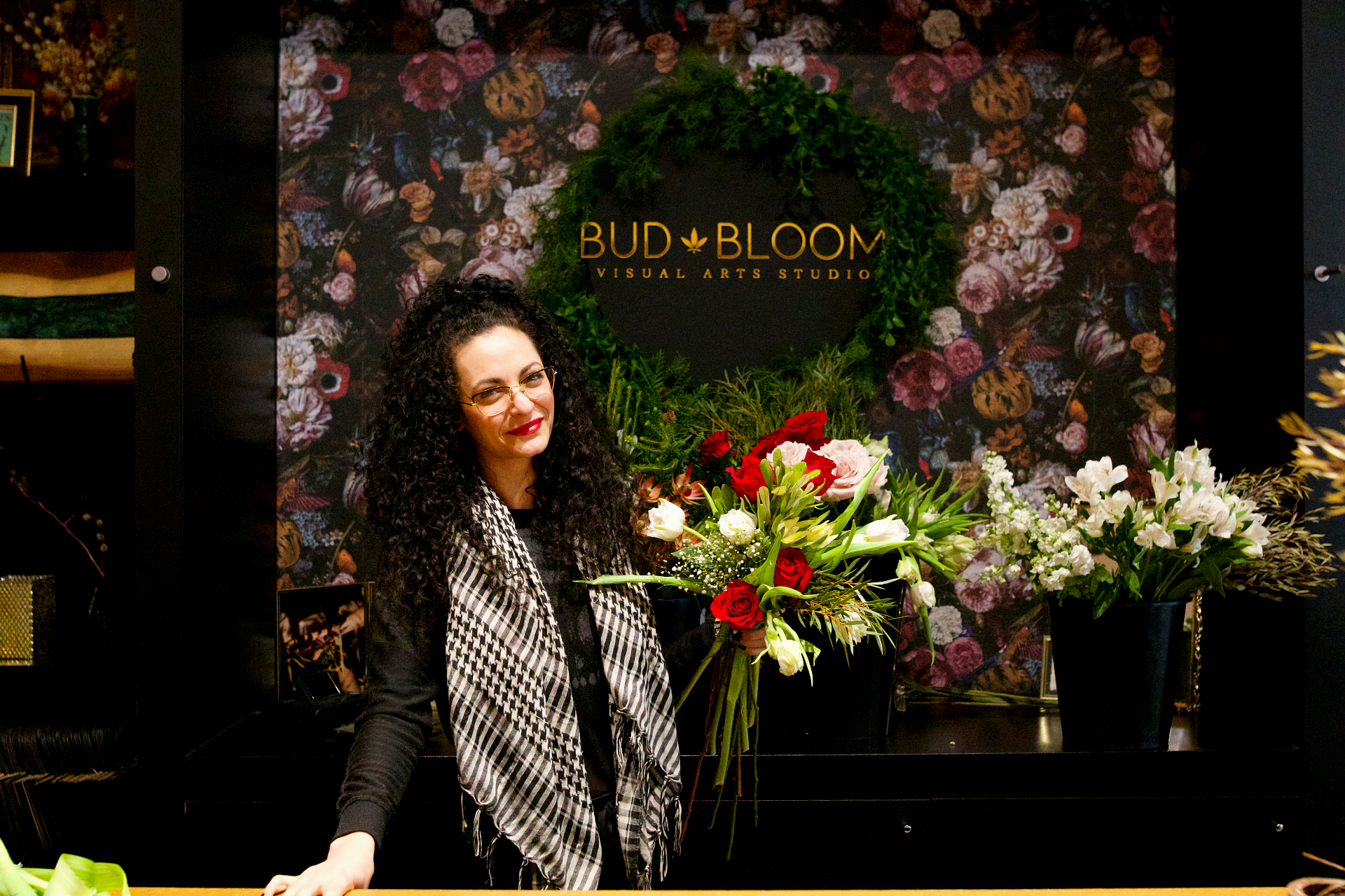 woman holding a bouquet of flowers in front of Bud and Bloom Visual Arts Studio sign