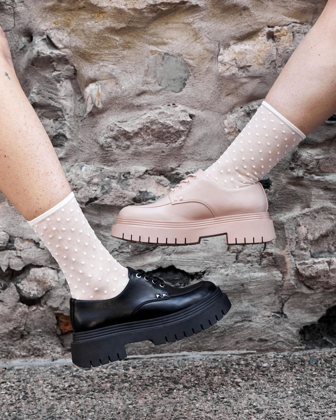 close-up of two model's feet. one is wearing black loafers and one is wearing pink loafers