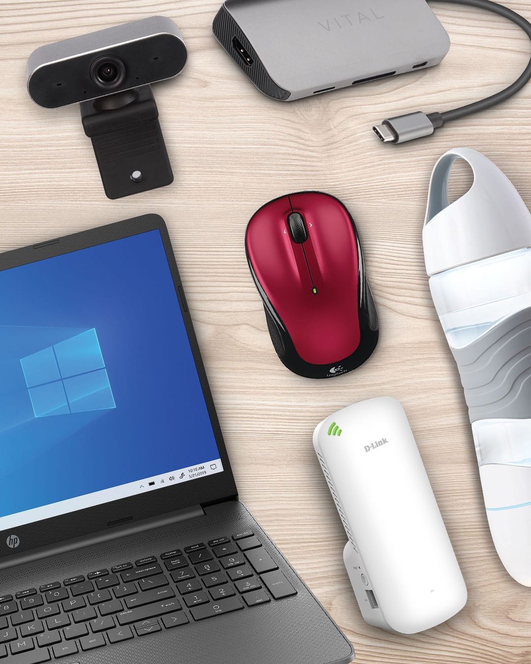 flat lay image of electronics including a laptop, a mouse, a portable webcam