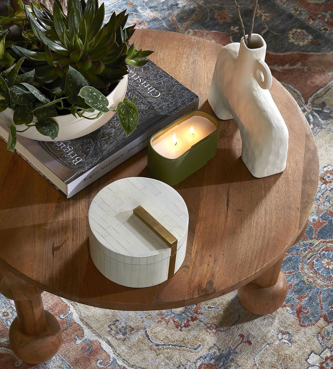 wooden side table with home decor including a candle, vase, plant, and decorative box