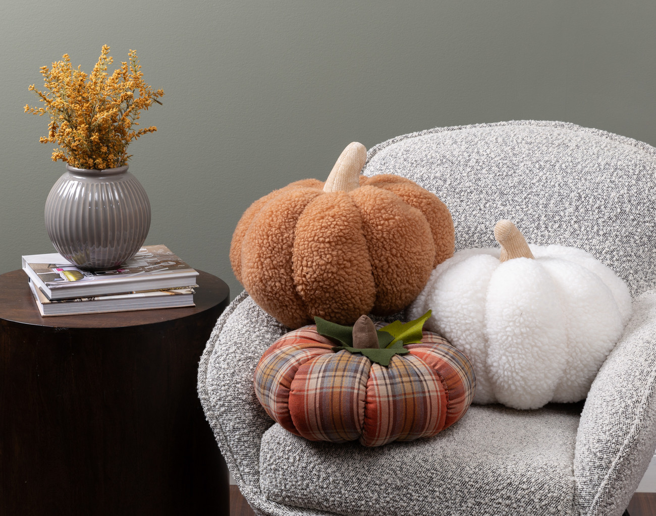 white, brown, and plaid plush pumpkins on a cozy armchair next to a table with decor