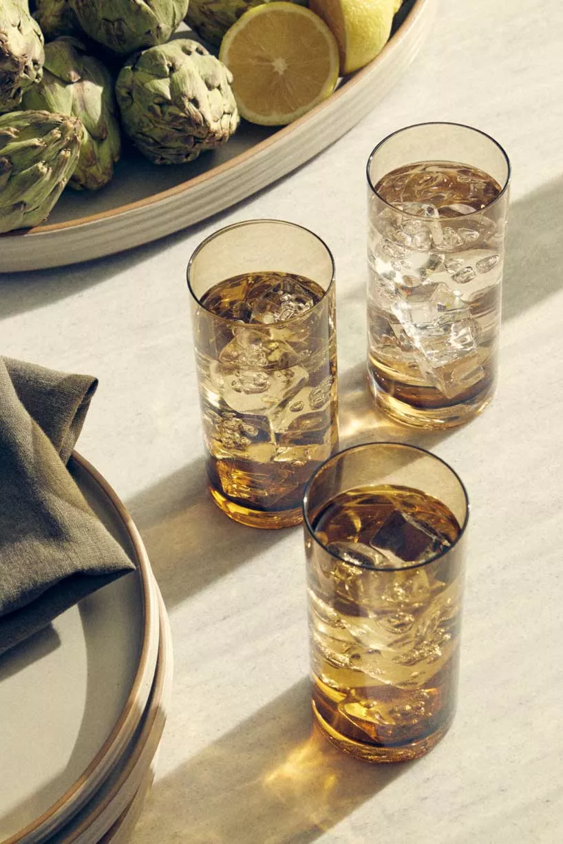 set of drink glasses on a table beside dishware