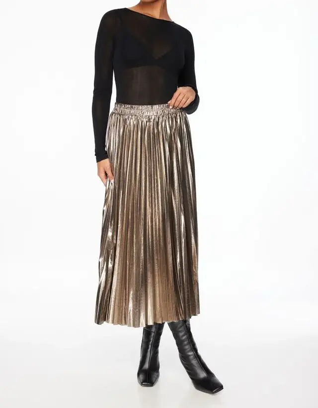 model wearing gold skirt and black mesh long sleeve top