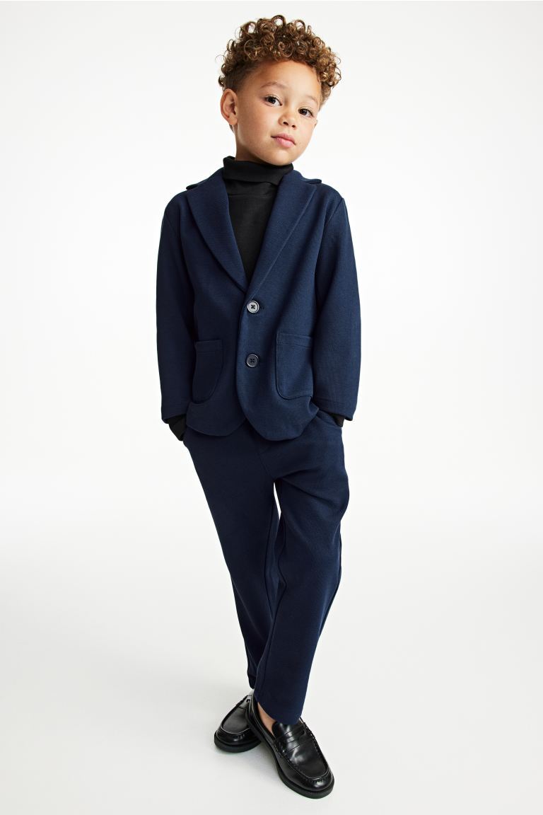 boy wearing blue suit with black turtleneck and black dress shoes