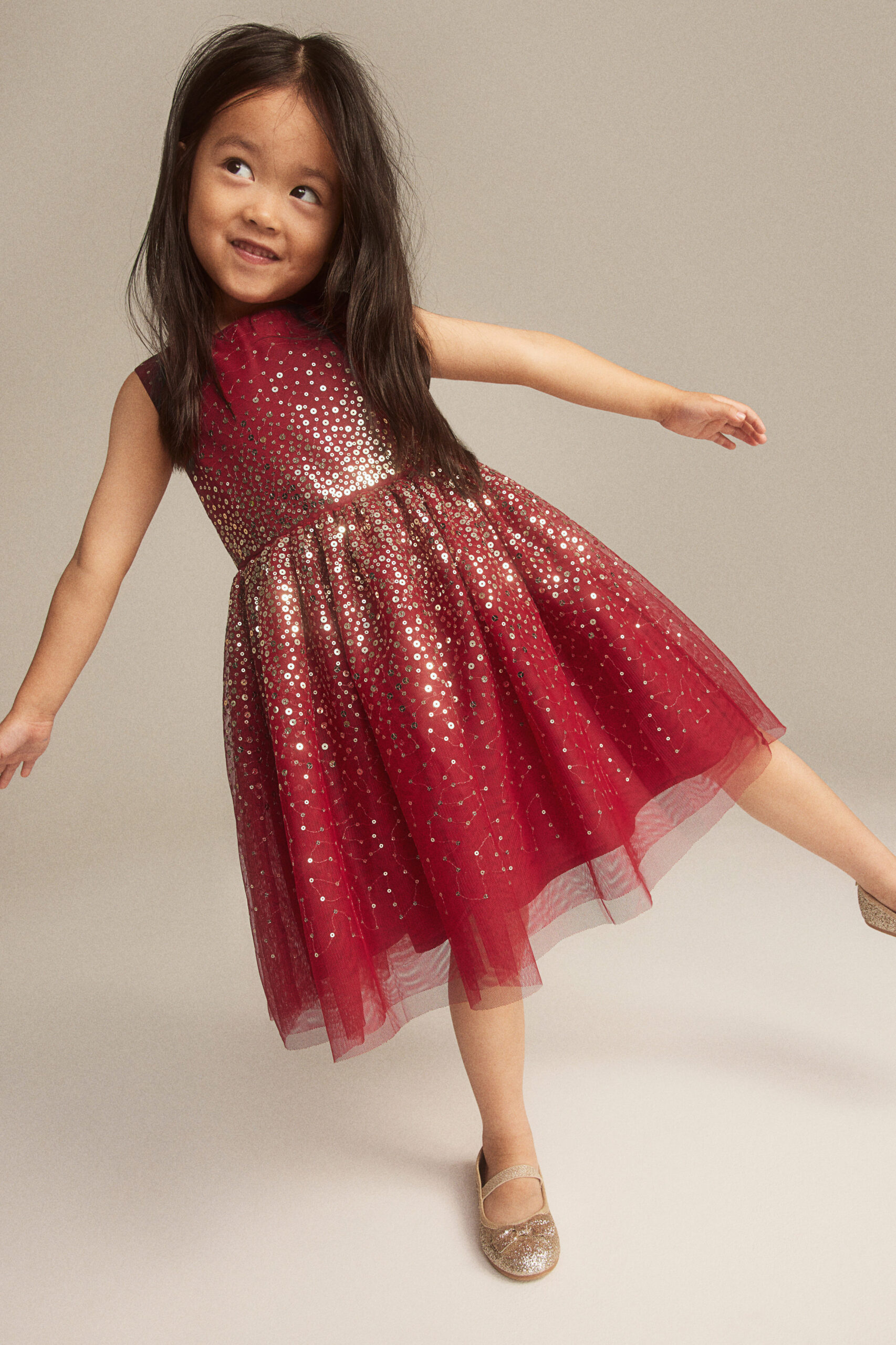 girl posing in red dress with gold sparkles and gold shoes