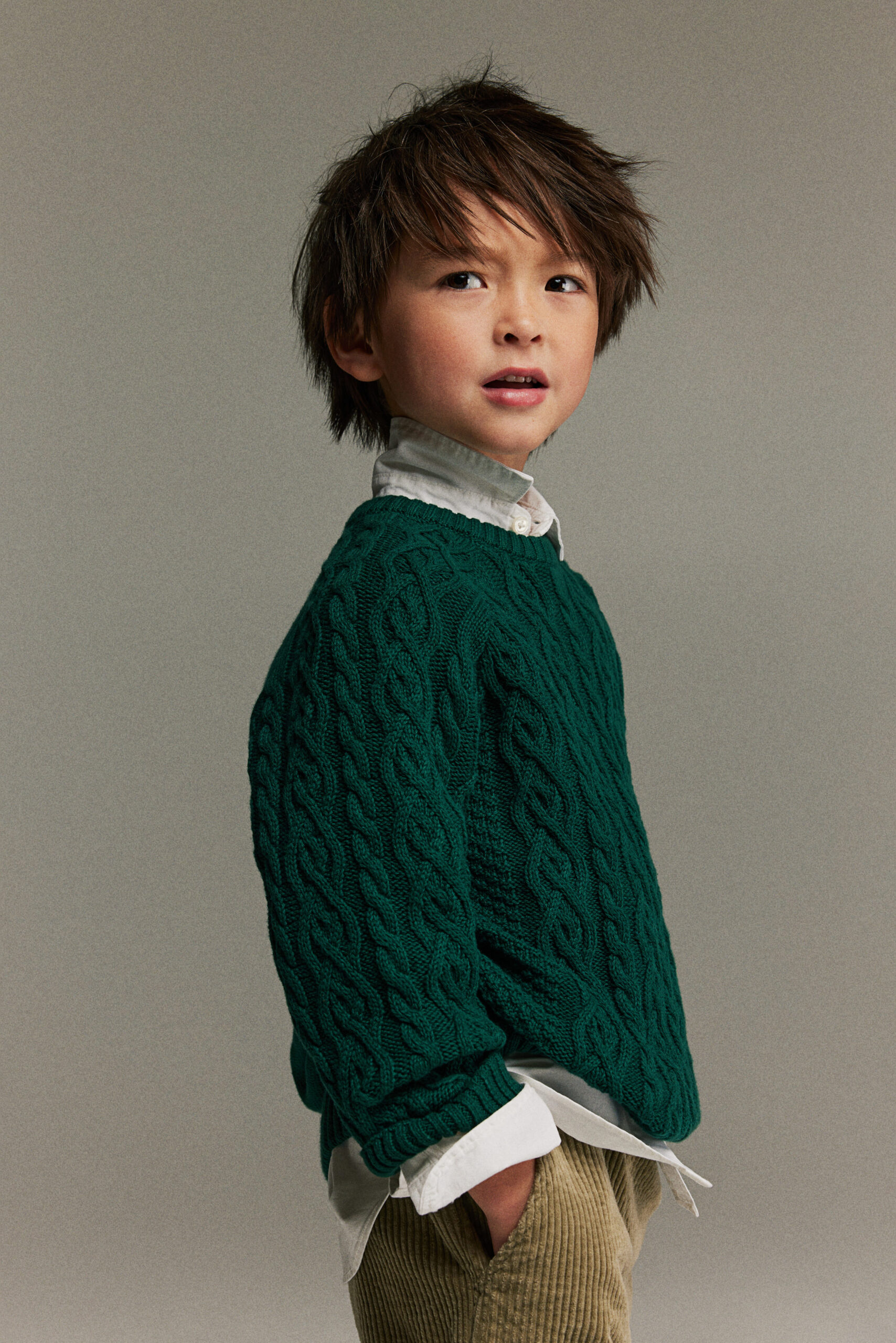 boy wearing green knit sweater over a button up shirt with corduroy pants