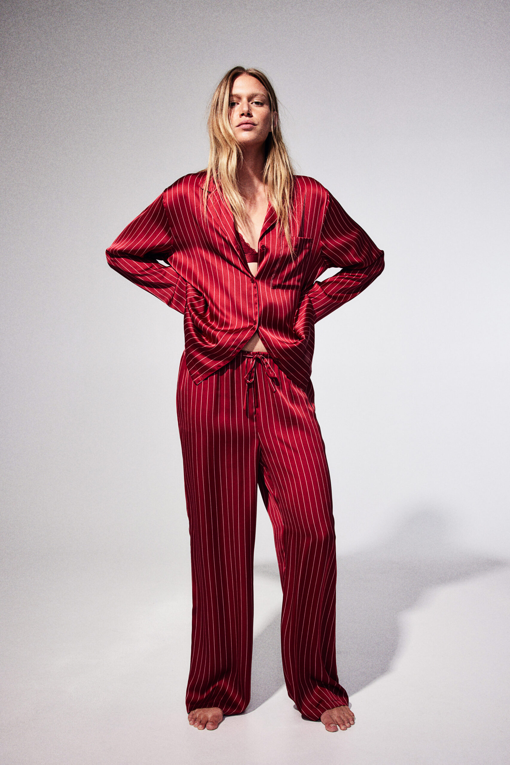 woman wearing long sleeve and pants red pinstriped pajama set