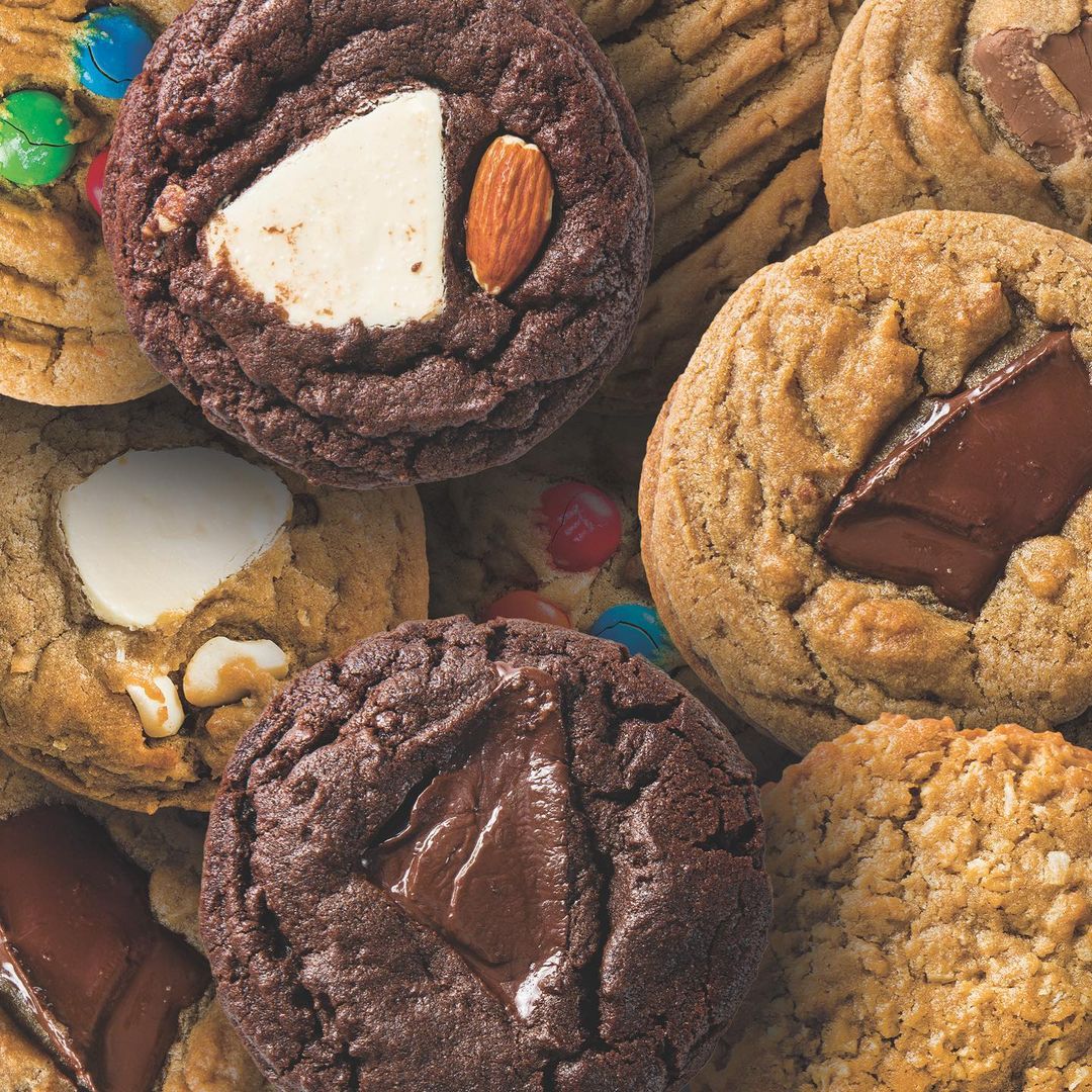 close up photo of a variety of cookies, including chocolate chunk, peanut butter, and M&M's