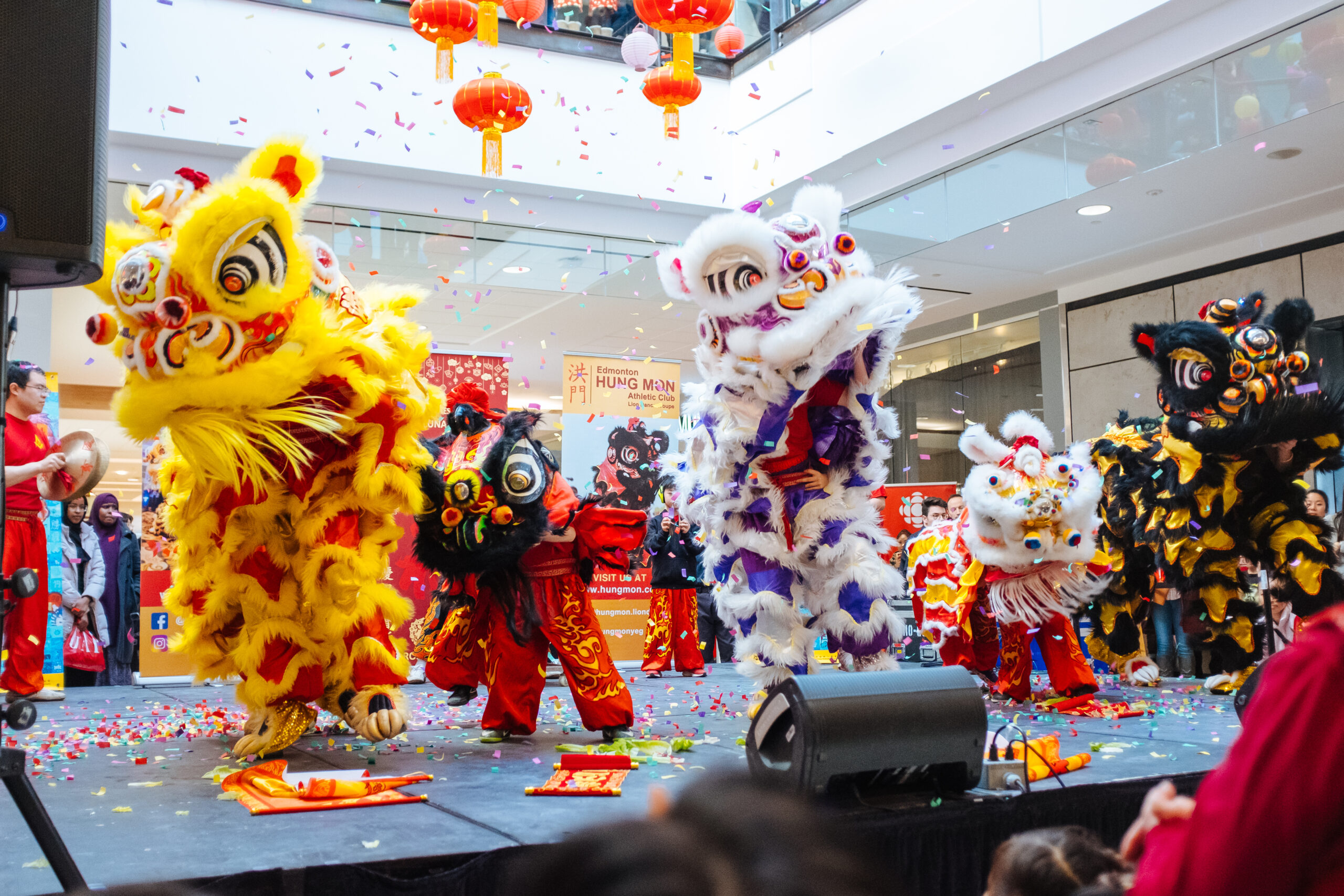 lion dance performance with colourful lions on stage with confetti falling