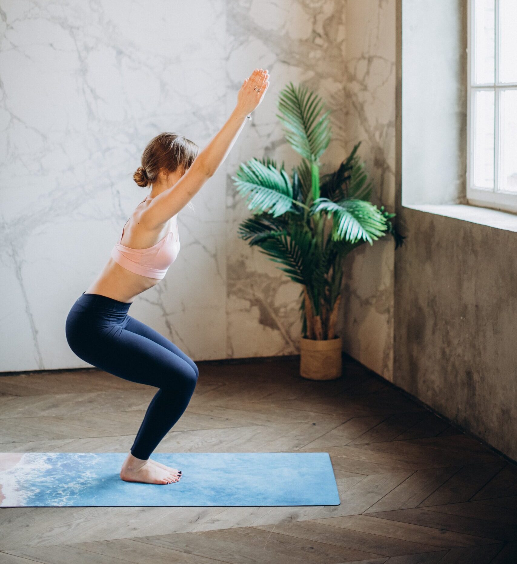 woman wearing sports bra and leggings doing yoga on mat