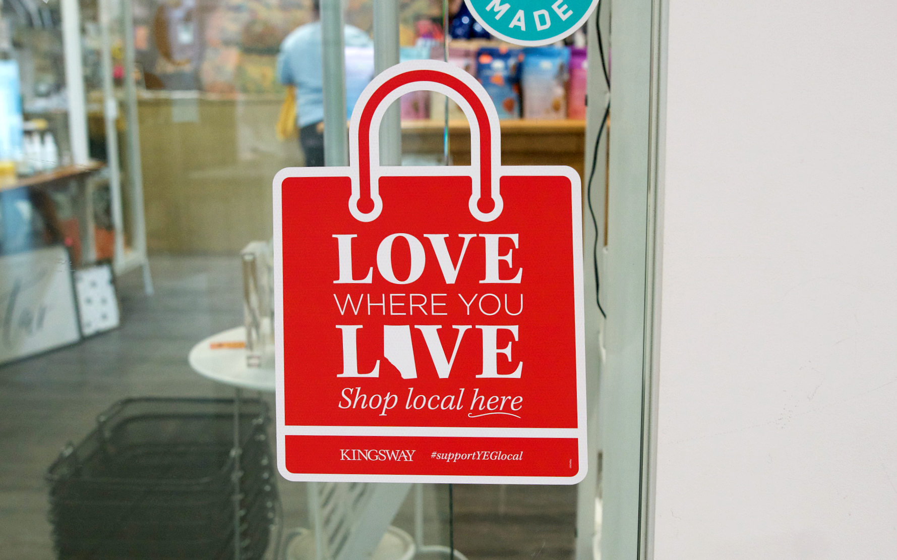 Red shopping bag window decal promoting shopping local with 'Love Where You Live' message