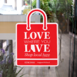 Window decal of red shopping bag with "Love Where You Live" message to shop local