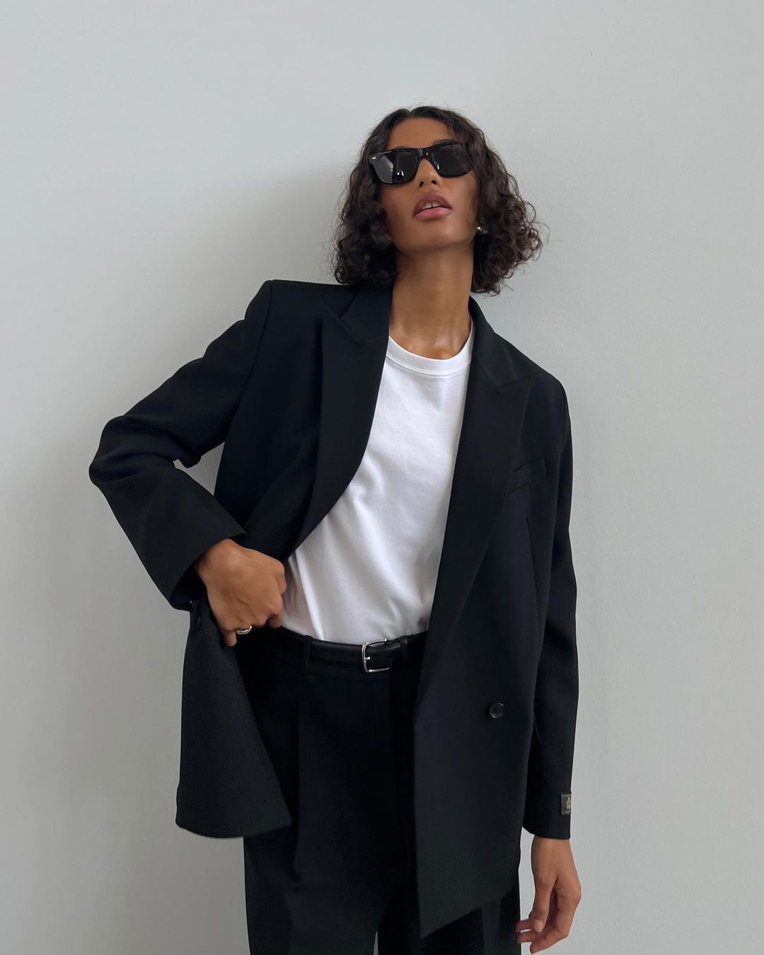 model wearing black blazer and pants, with white shirt and sunglasses