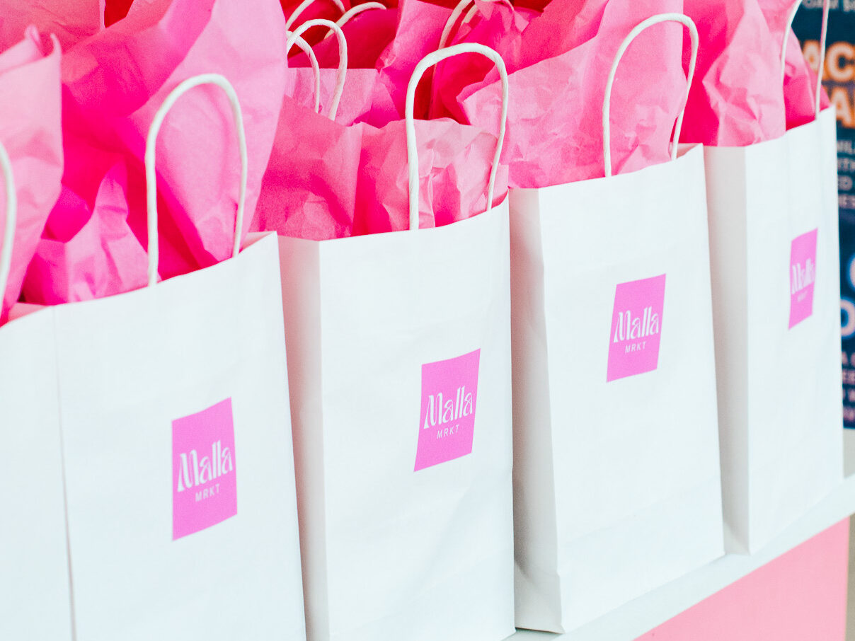 white gift bags with pink tissue paper and Malla MRKT stickers
