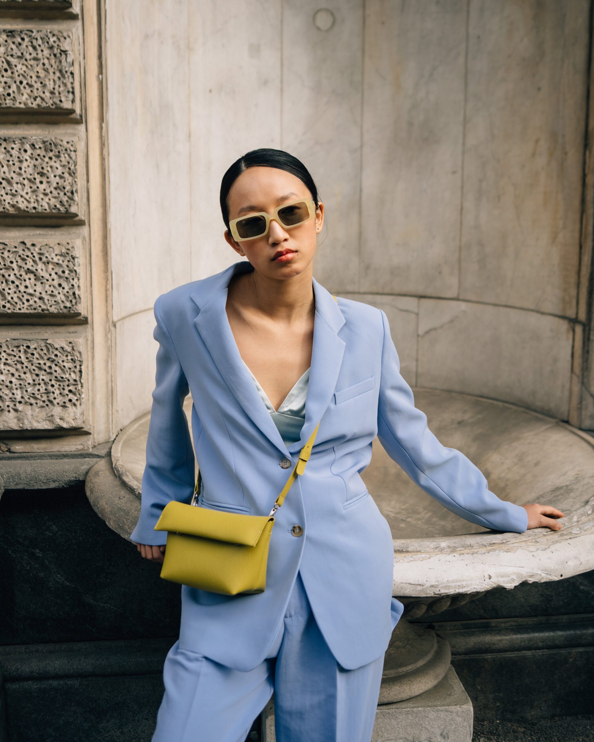 model wearing baby blue suit and yellow purse