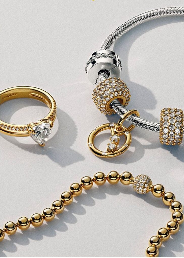 diamond ring with gold band, pandora charm bracelet with gold and silver charms, and gold beaded necklace