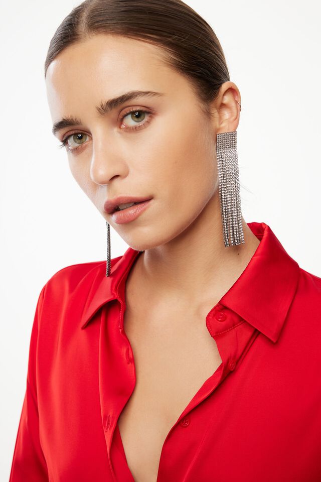 model wearing red satin blouse and silver dangle earrings
