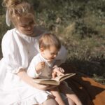 mother in white dress reading to her baby