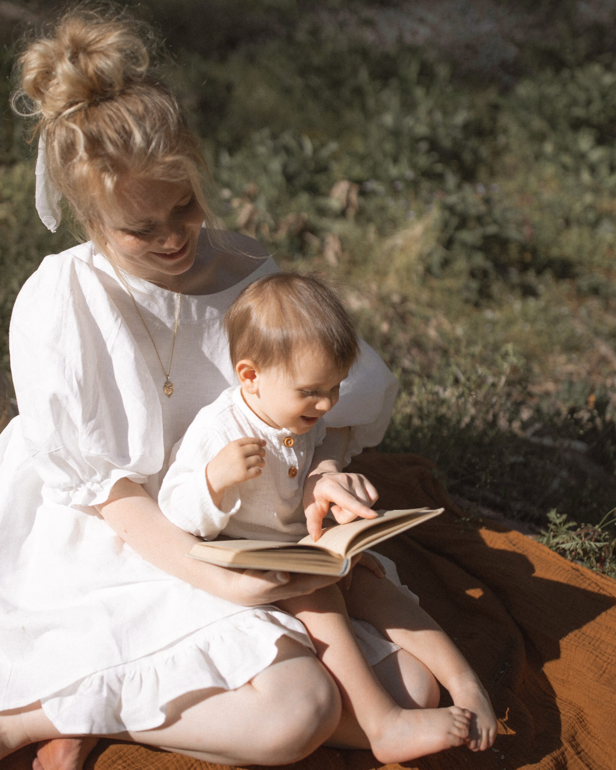 mother in white dress reading to her baby