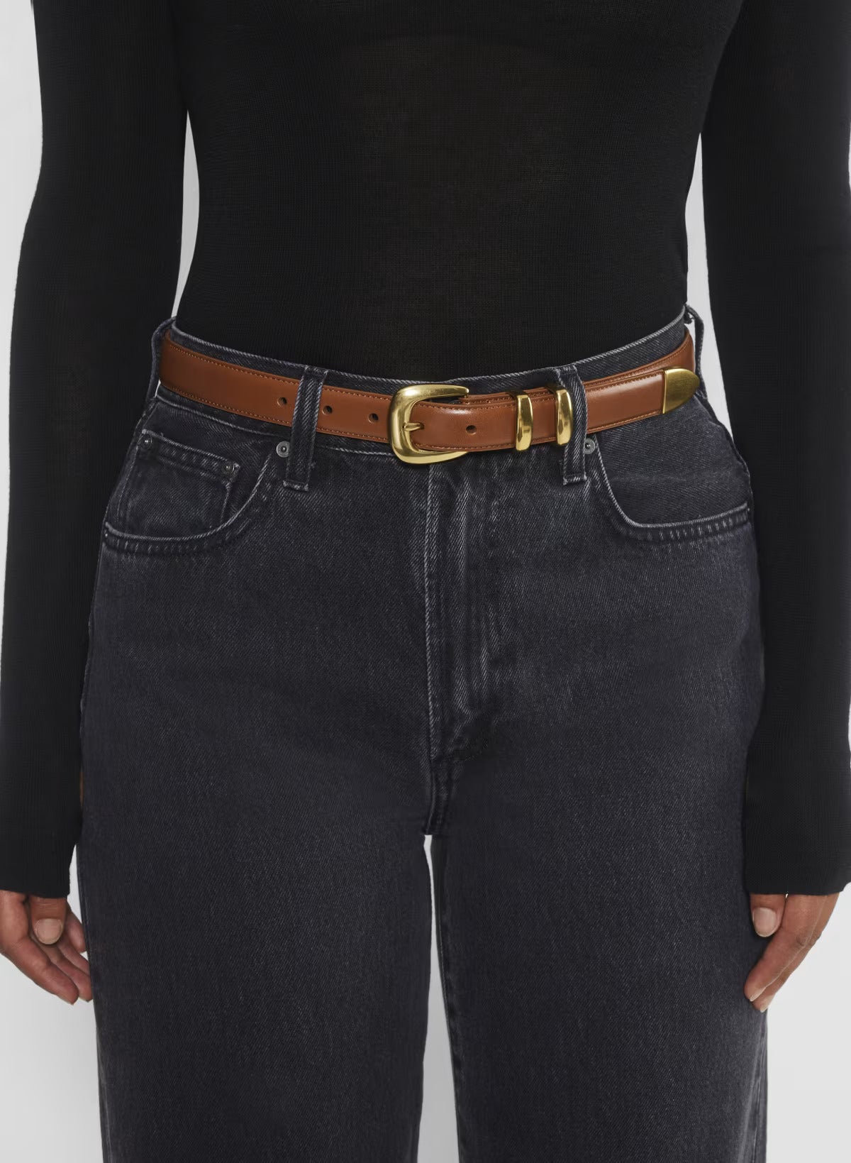 model wearing tight fitted black long sleeve top and black jeans with brown buckle