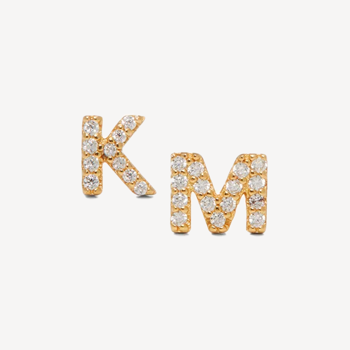 Gold and diamond earring studs, in the shape of letters 'K' and 'M'