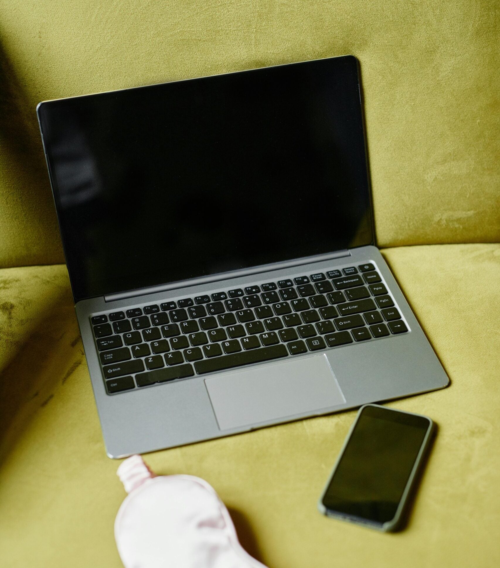 Laptop, eye mask, and smartphone on green background