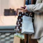 Woman and Man holding shopping bags outside of a store.