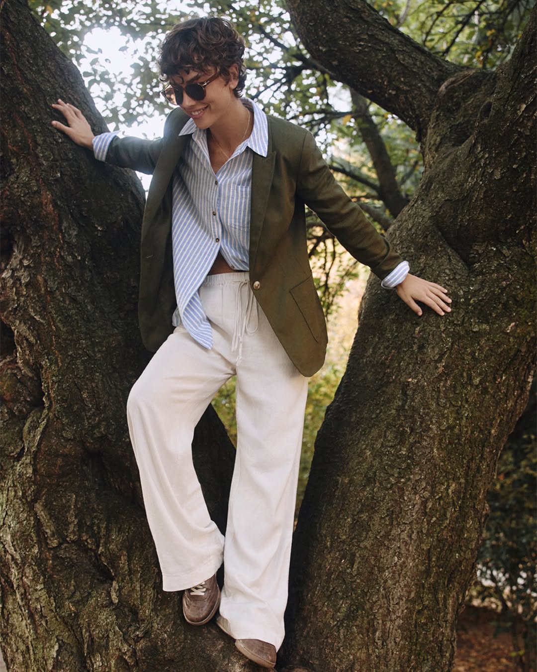 woman wearing blue white striped button down, beige pants, and green blazer