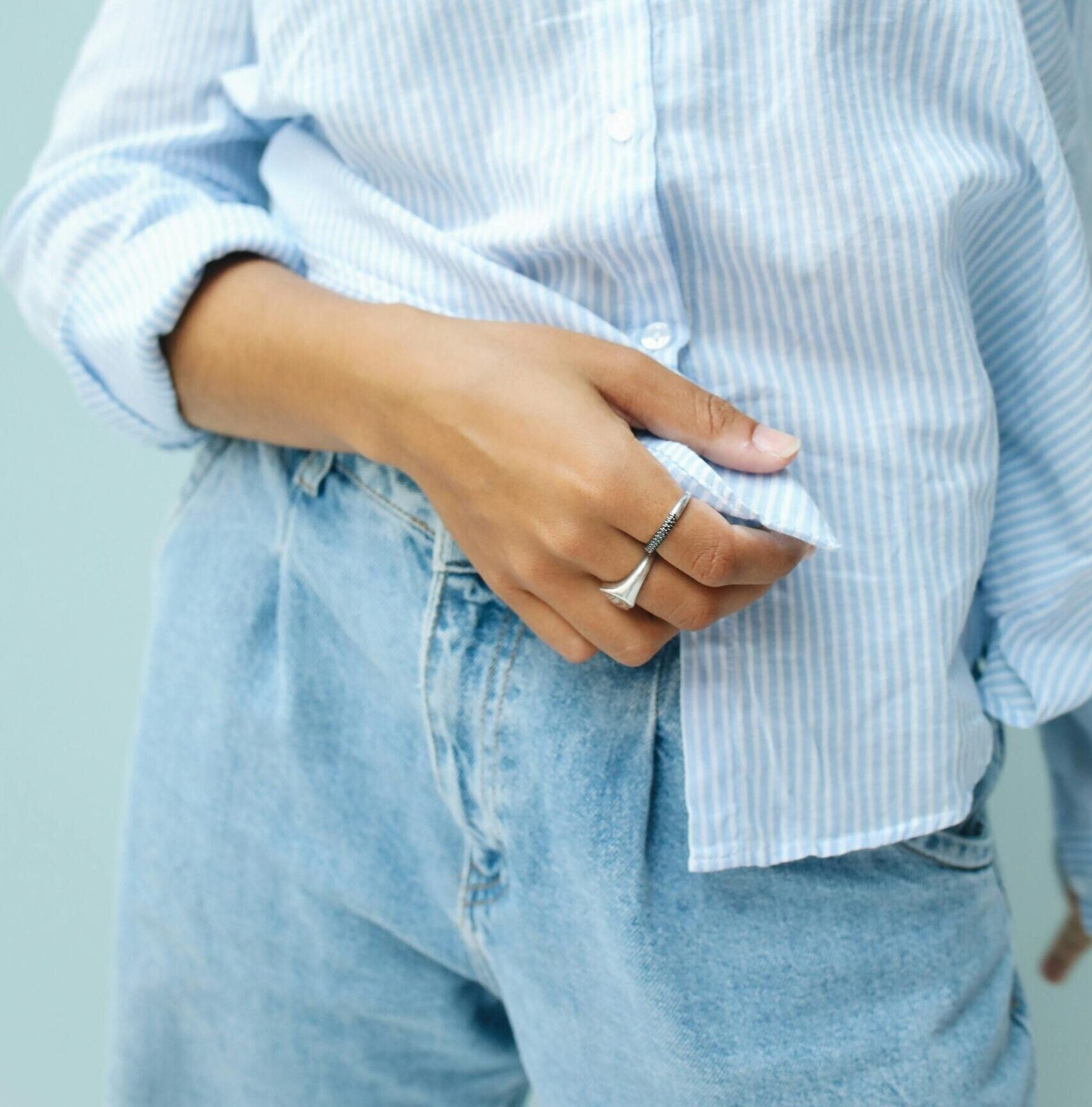 model wearing blue white striped button down and jeans