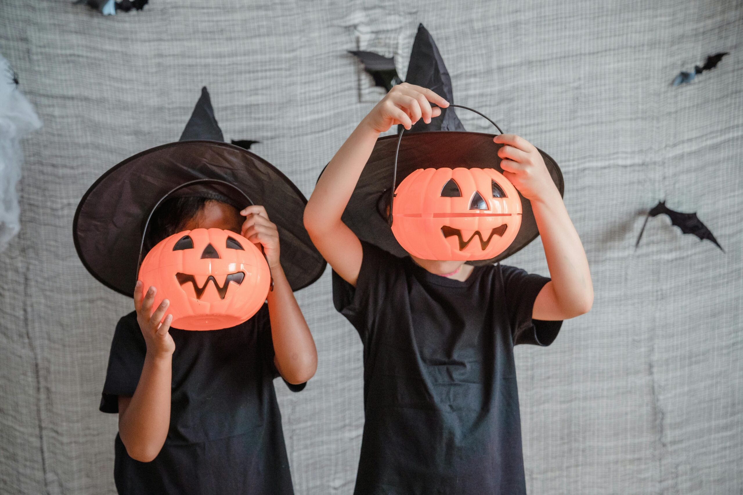 two children covering faces with pumpkins