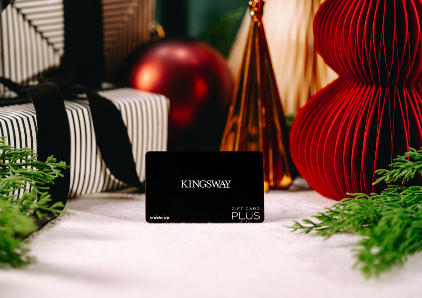 Black Gift Card in front of Presents & greenery