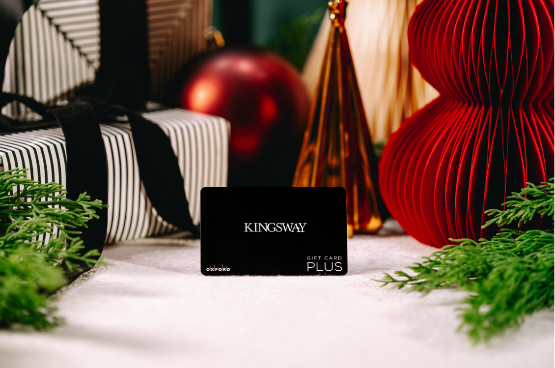 Black Gift Card in front of Presents & greenery