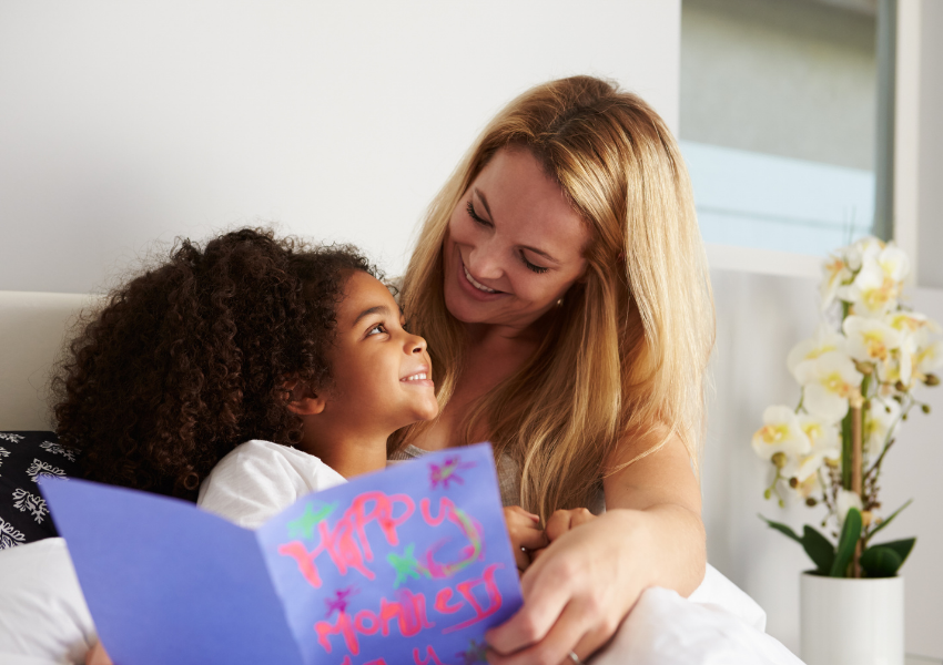 Mom & Daughter with card in bed